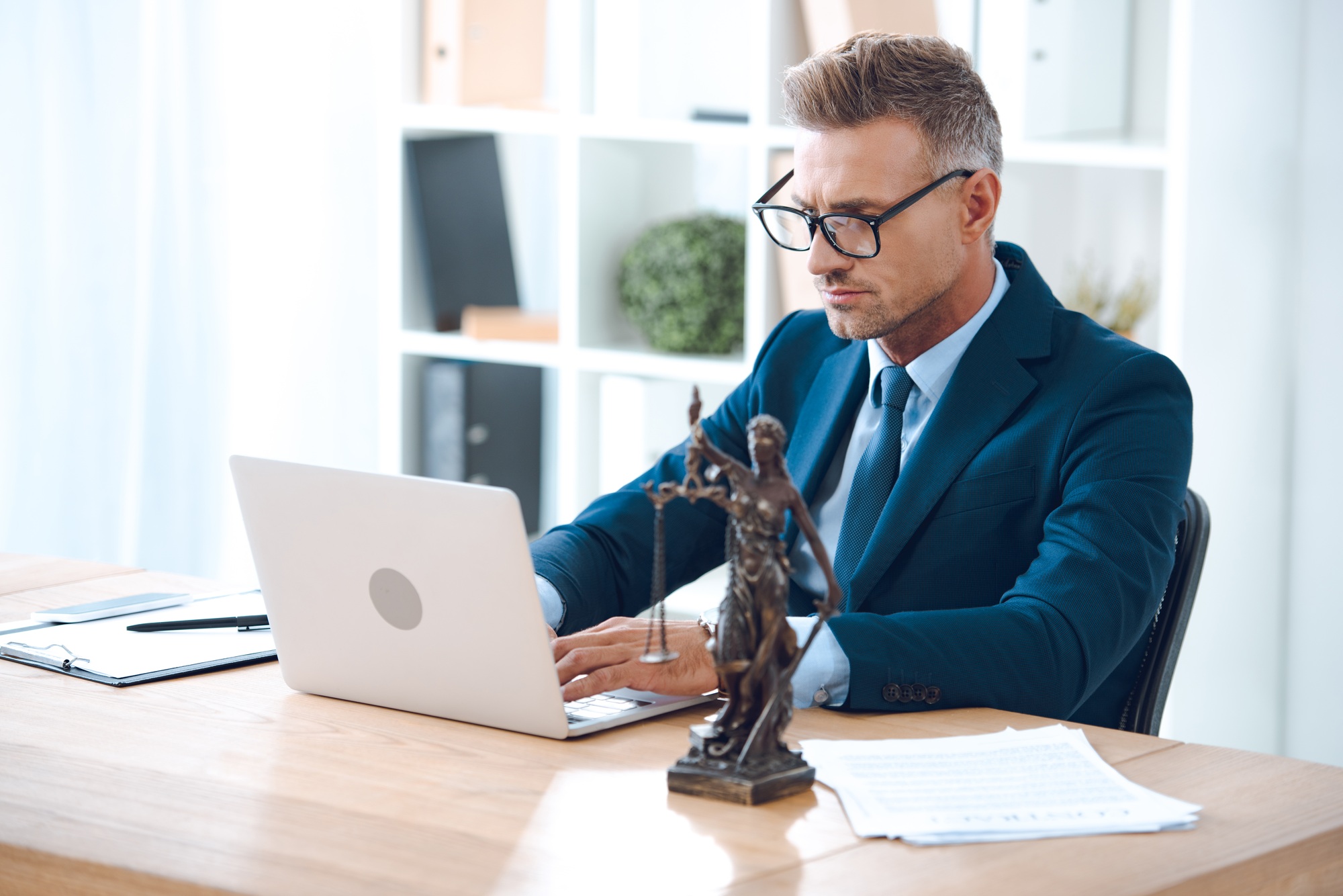 handsome lawyer in eyeglasses using laptop at workplace